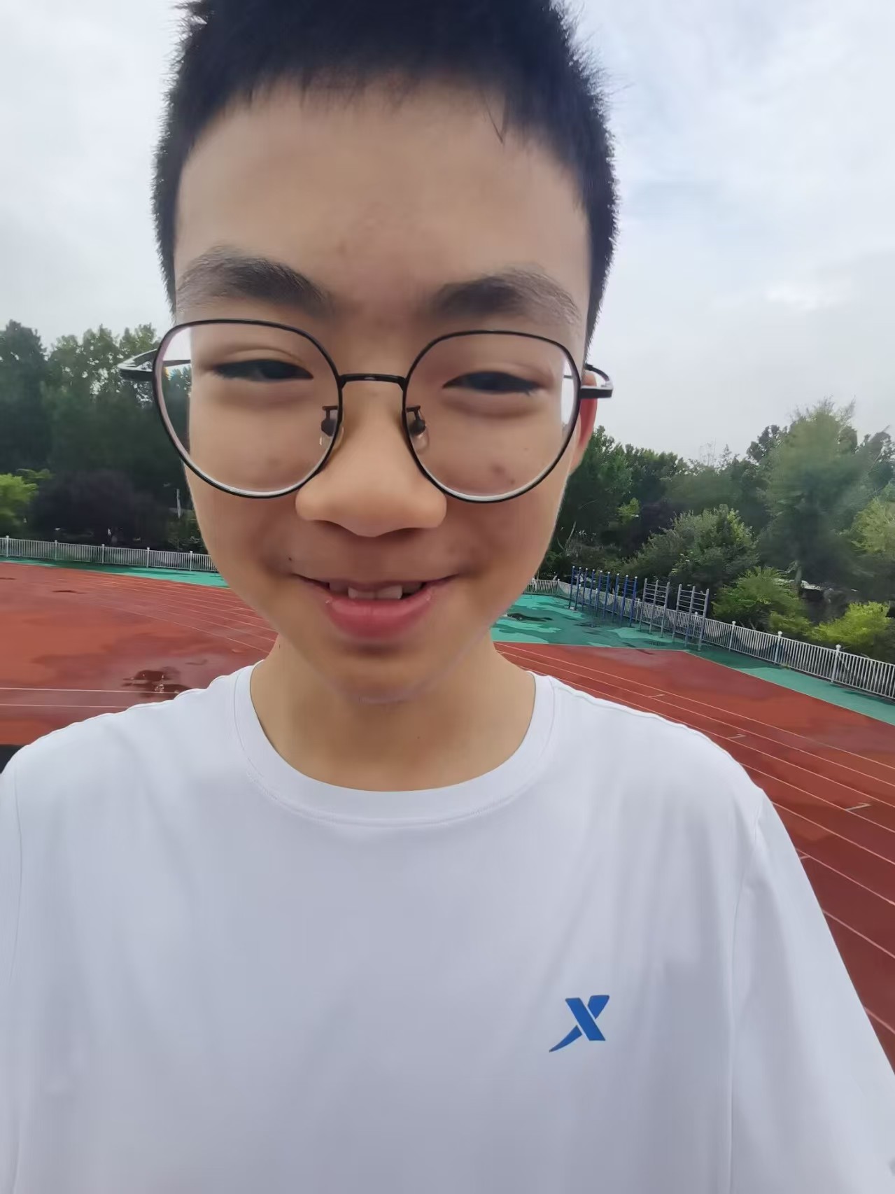 配泼睿在田径场穿白色T恤微笑